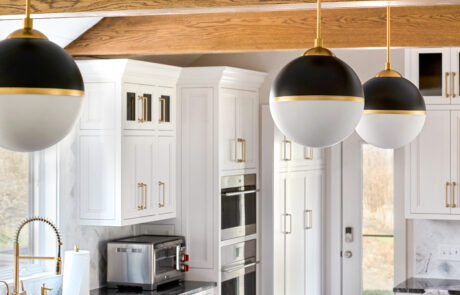 Kitchen with white custom cabinetry, gold finishes and exposed ceiling beams