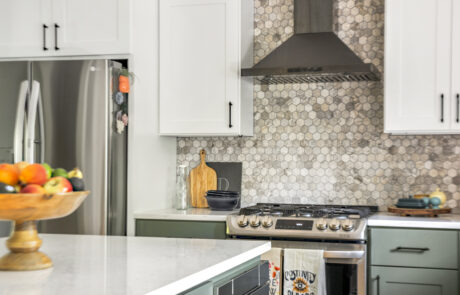 Kitchen remodel with gas range and black stainless steel range hood.